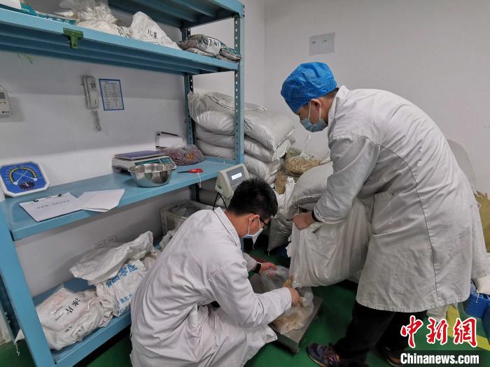图为药师们对照自制剂的配方和处方量，对其进行称重调配。　赵晓 摄