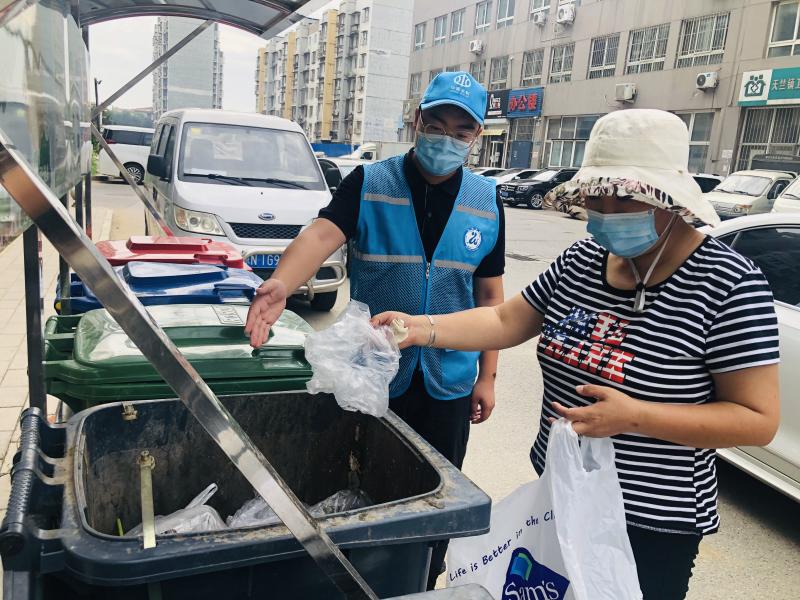 水务局志愿者谭享在指导居民进行正确垃圾分类.jpeg