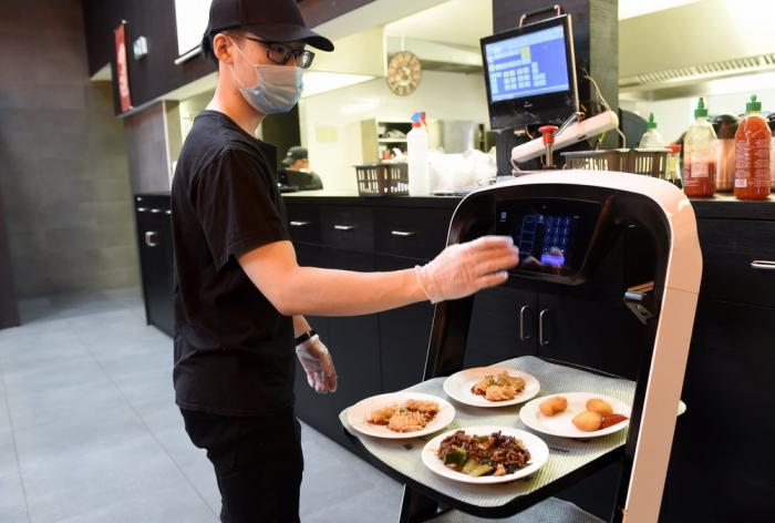 5月28日,在奥地利维也纳一家亚洲餐厅内,服务员为机器人设置送餐桌号